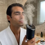 Los beneficios de vaporizar tu cara: la técnica de grooming que revoluciona el cuidado facial masculino Hombre usando vaporizador facial moderno en rutina de grooming de lujo