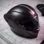 Casco de moto premium de fibra de carbono con acabado profesional sobre superficie de mármol
