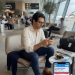 Vacaciones de último minuto: ventajas que te sorprenderán Hombre consultando ofertas de último minuto en su smartphone en el aeropuerto